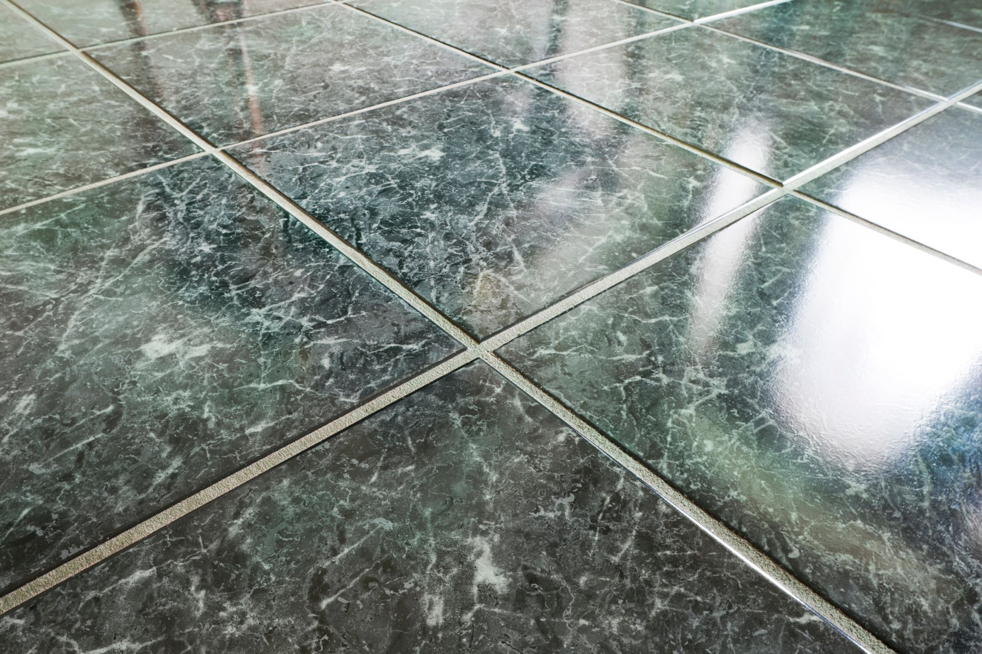 A close up of a green tiled floor with a white border.