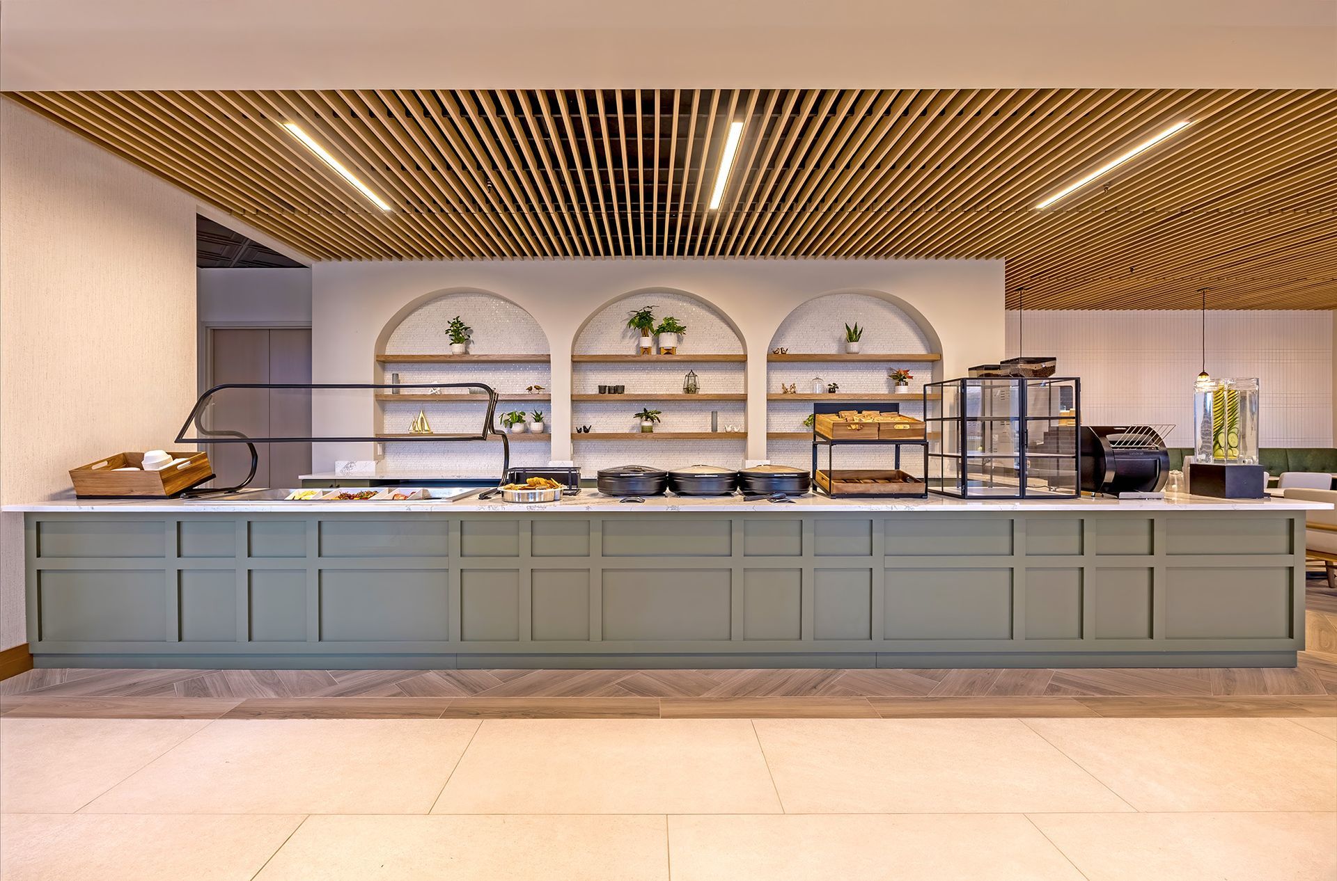 Buffet counter with pastries, shelves, and wood ceiling. Counter is sage green with marble countertop.