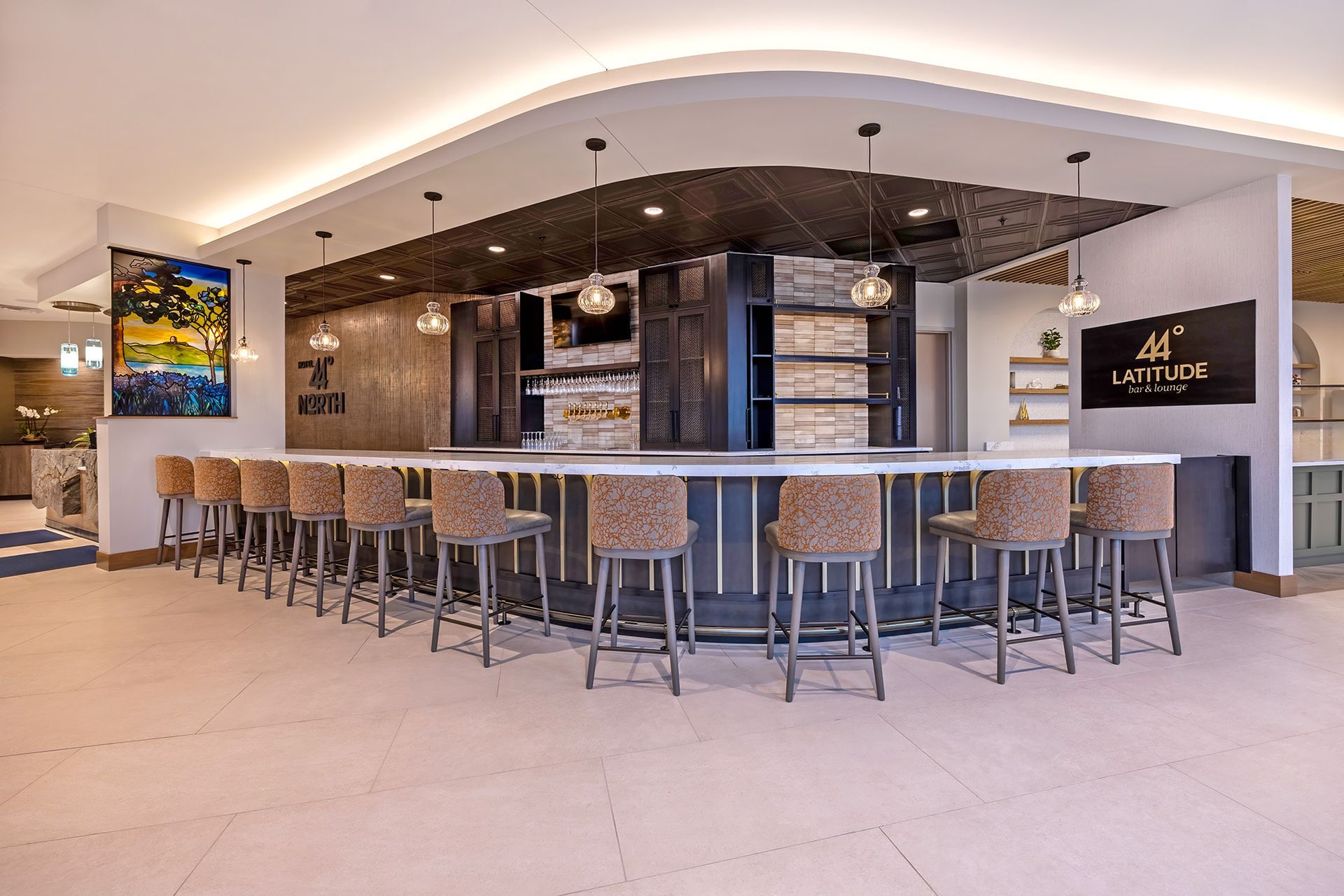 A modern bar with stools, a wood and tile backdrop, and overhead lighting.