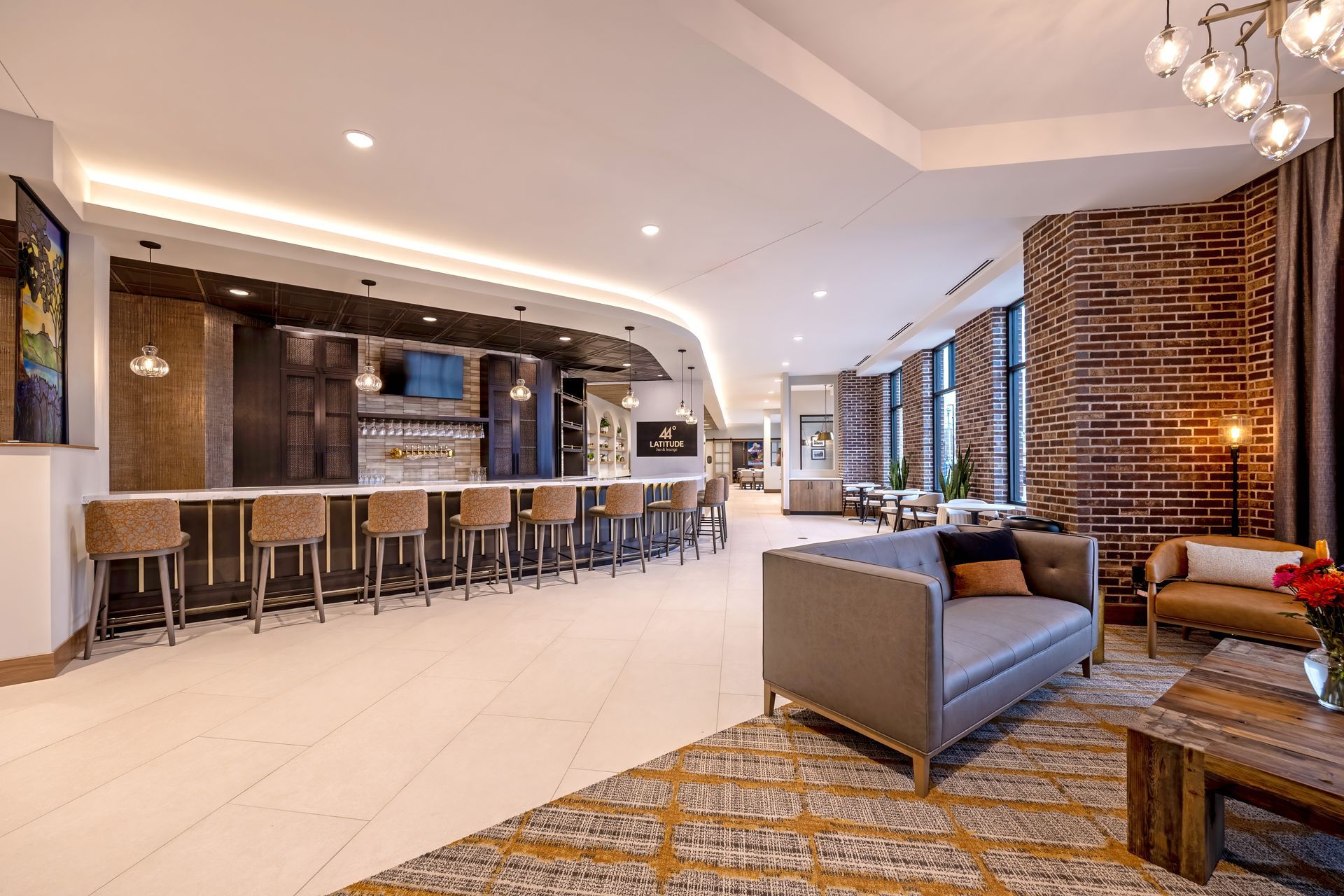 Upscale bar and lounge with bar stools, exposed brick, and seating area.