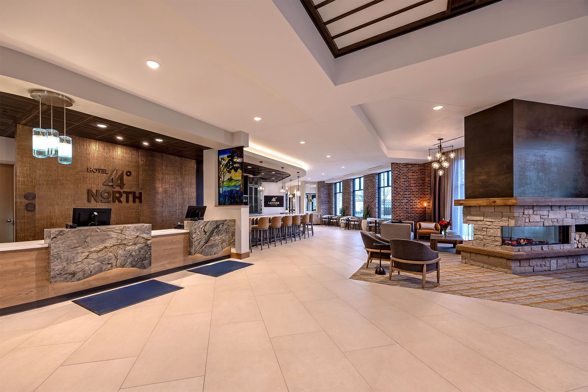 Hotel lobby with reception desk, bar, fireplace, and seating area.