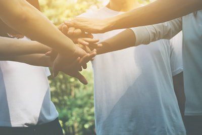 A group of people are putting their hands together in a huddle.