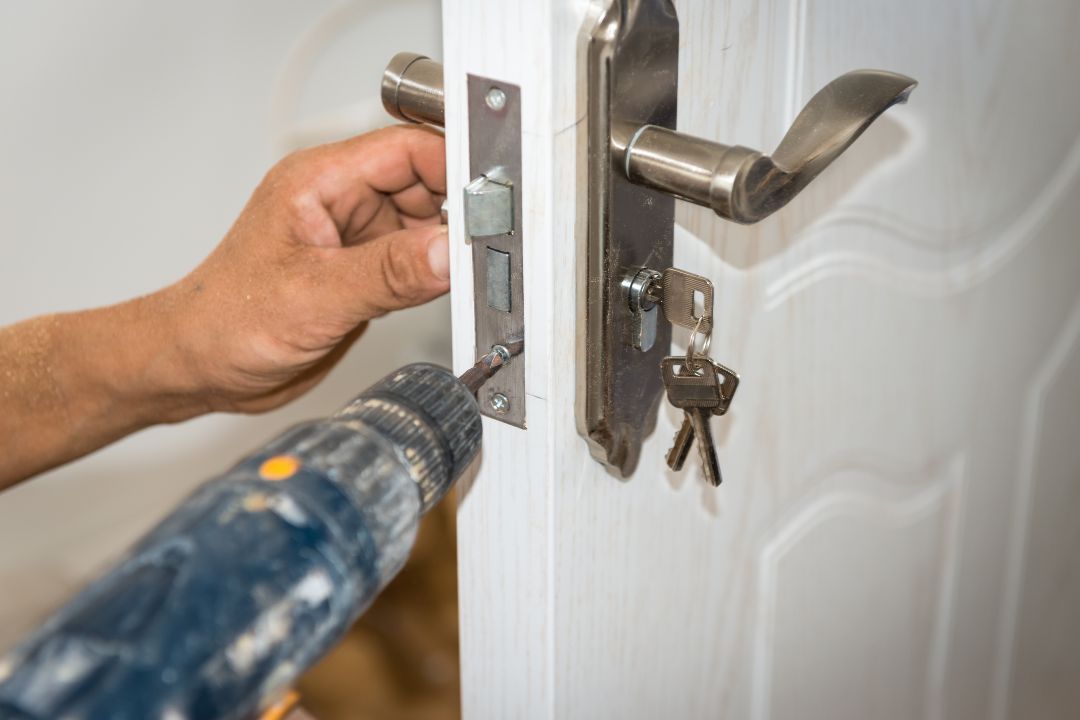 A man is fixing a door with a drill.