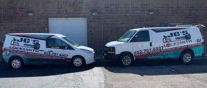 Two vans are parked next to each other in front of a building.