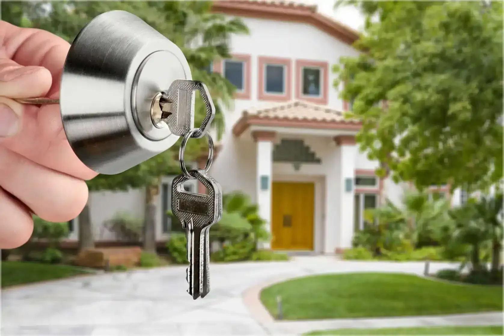 A person is holding a key in front of a house.