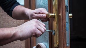 A man is fixing a door with a screwdriver.