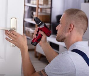 A man is fixing a door handle with a drill.