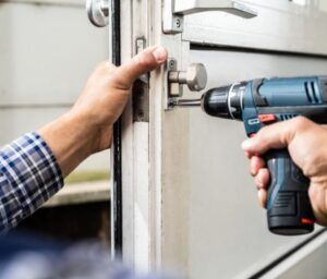 A man is fixing a door with a drill.