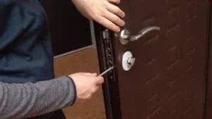 A person is opening a door with a screwdriver.