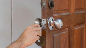 A person is opening a wooden door with a door knob.