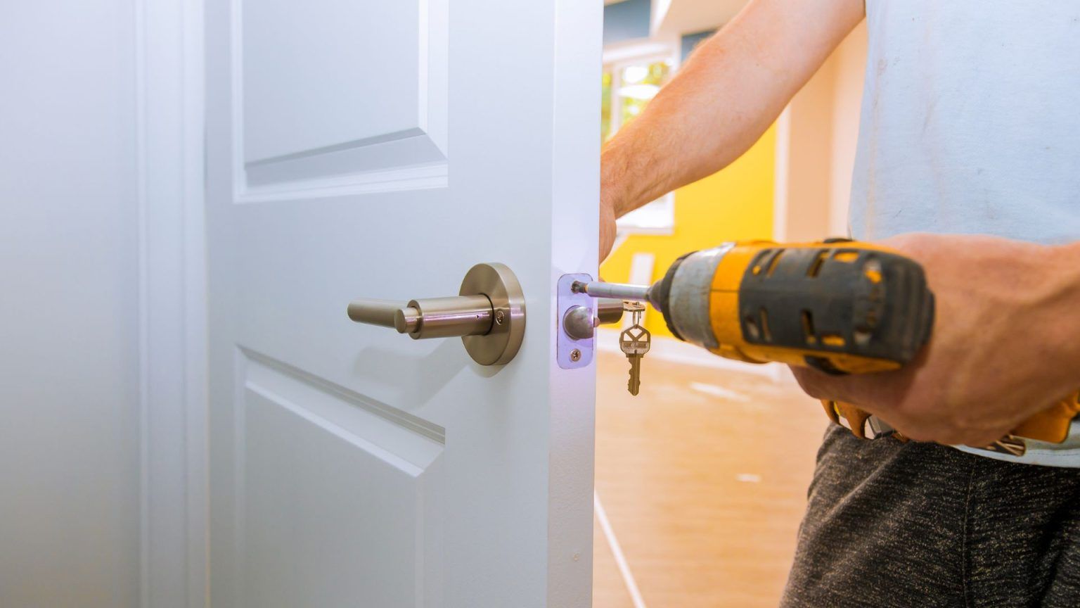A man is installing a door handle with a drill.