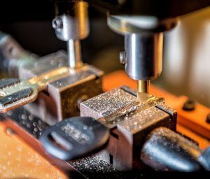 A close up of a machine cutting keys on a table.