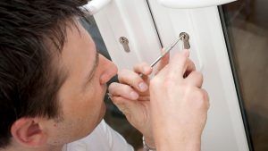 A man is using a screwdriver to fix a door lock.