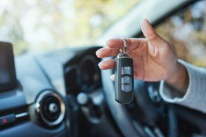 A person is holding a car key in their hand in a car.