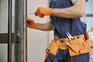 A man is fixing a door with a screwdriver.