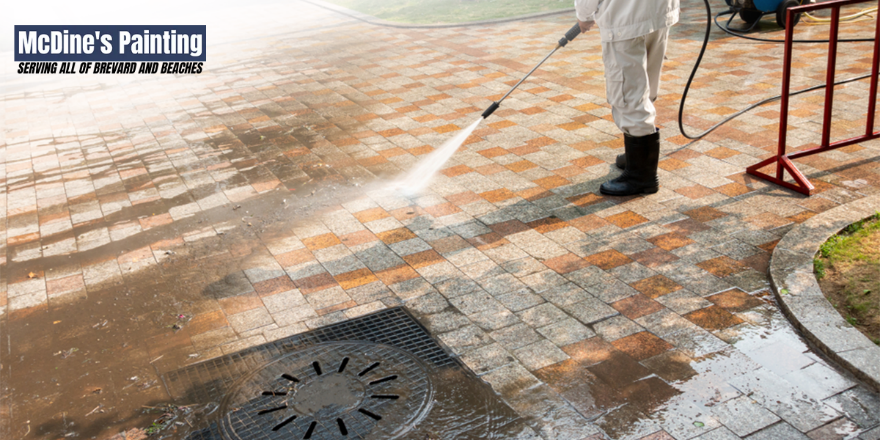 A man is using a high pressure washer to clean a manhole cover.