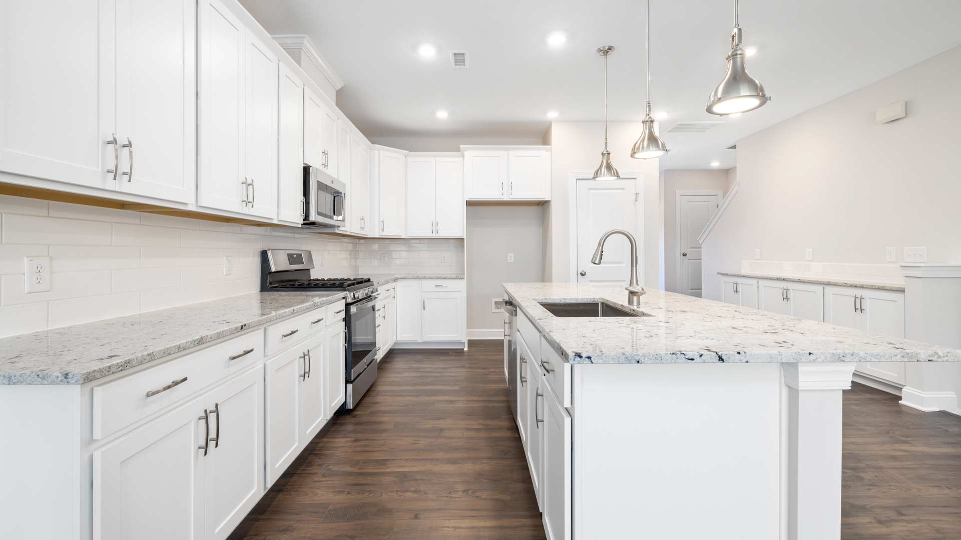 A kitchen with white cabinets , granite counter tops , and stainless steel appliances.