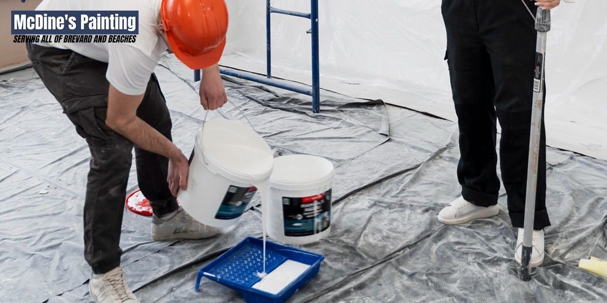 A man is pouring paint from a bucket into a tray.