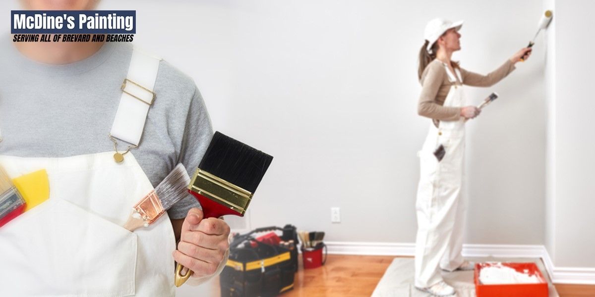 A woman is painting a wall and a man is holding a brush