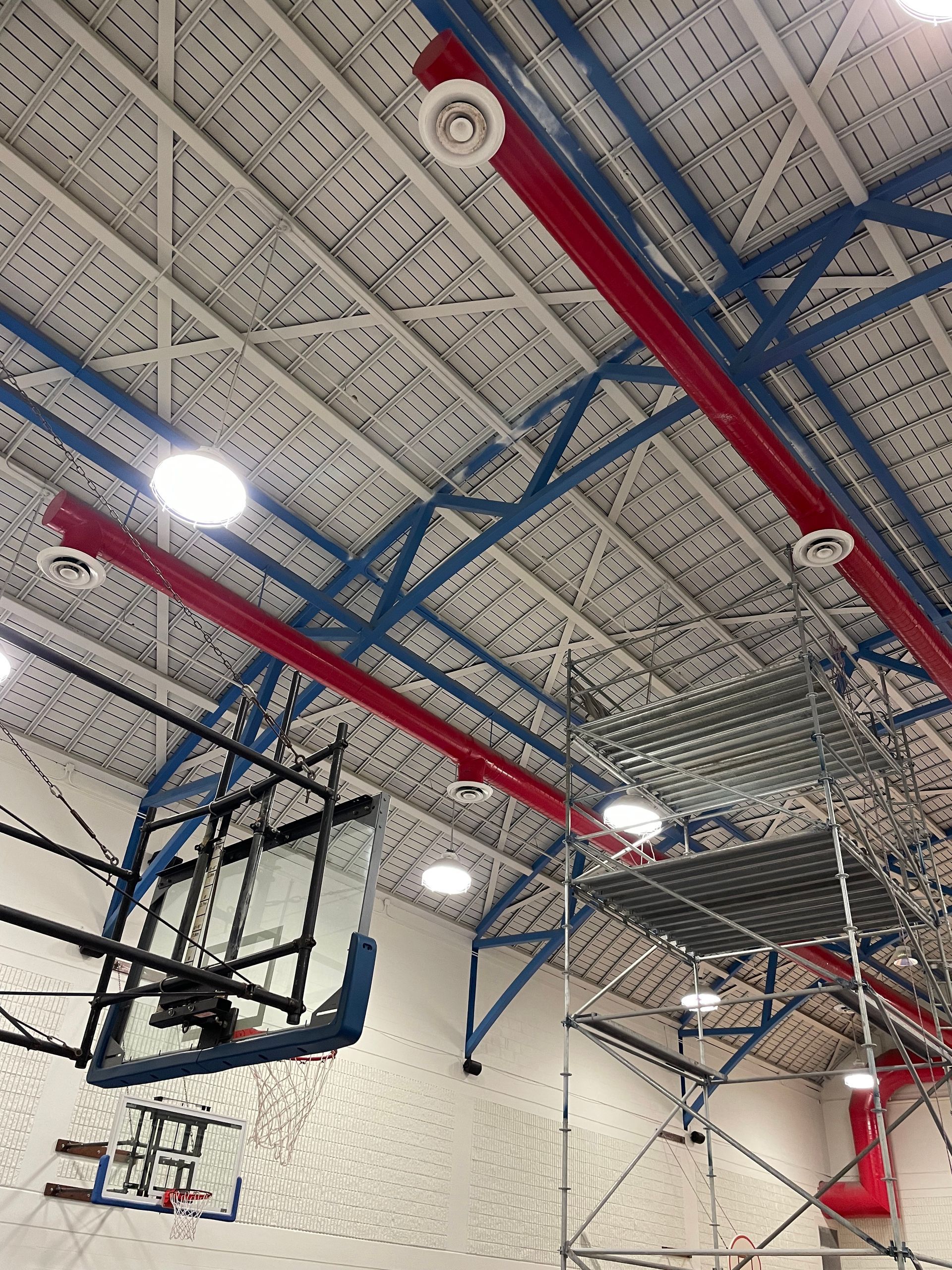A basketball hoop is hanging from the ceiling of a gym