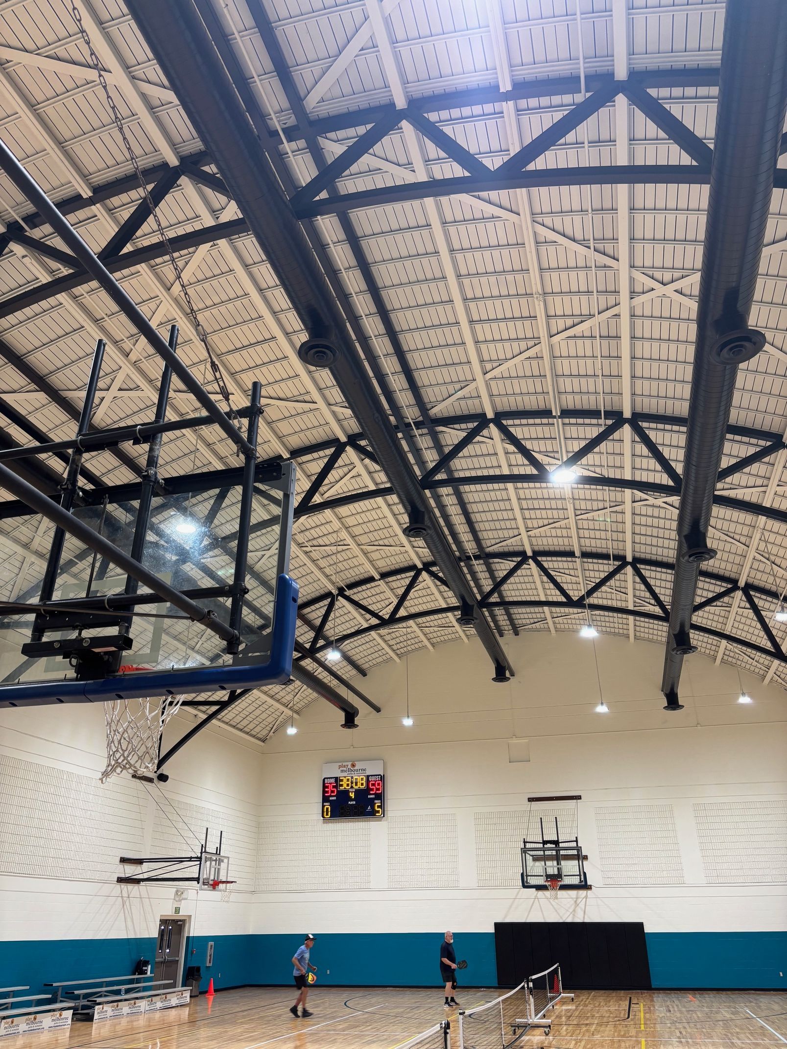 A basketball hoop is hanging from the ceiling of a gym.