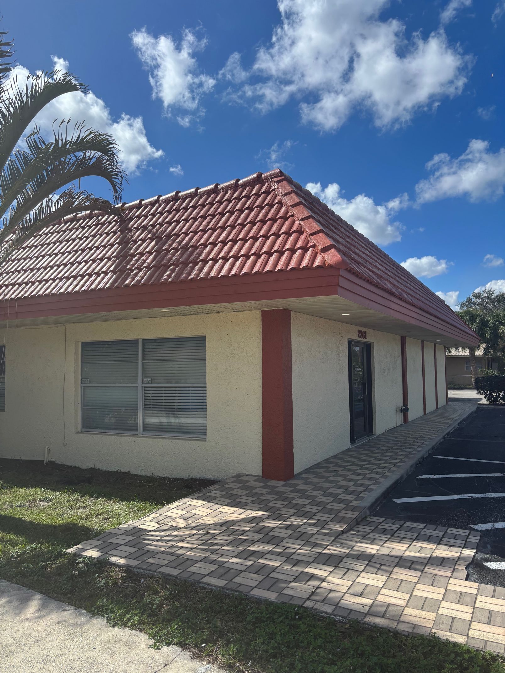 A white building with a red roof and a palm tree in front of it