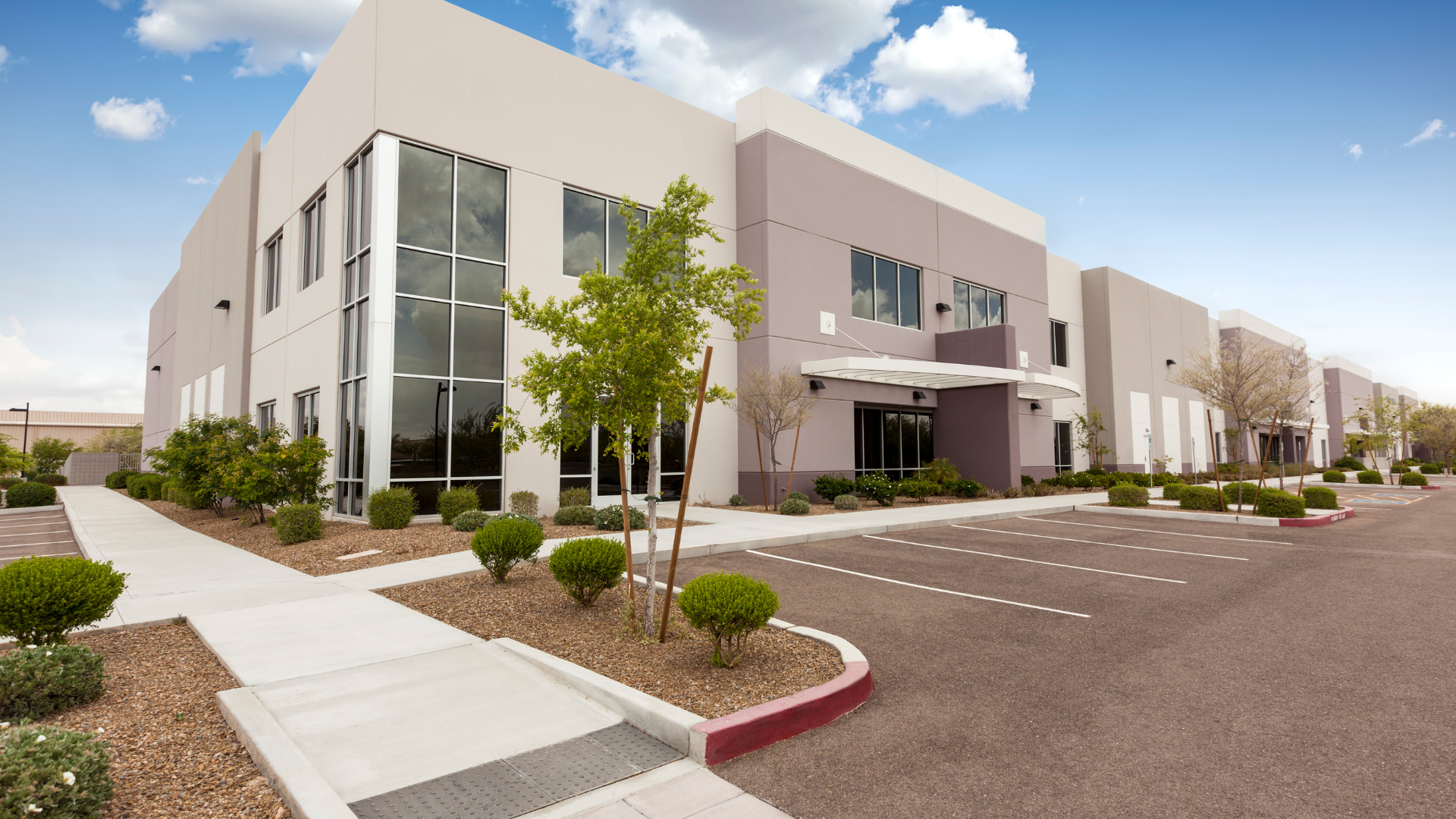 A large building with a lot of windows and a parking lot in front of it.