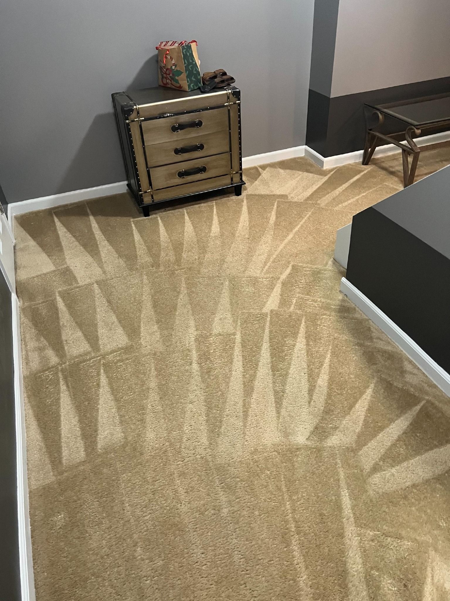 Beige carpet with a geometric design, nightstand, and dark gray walls.