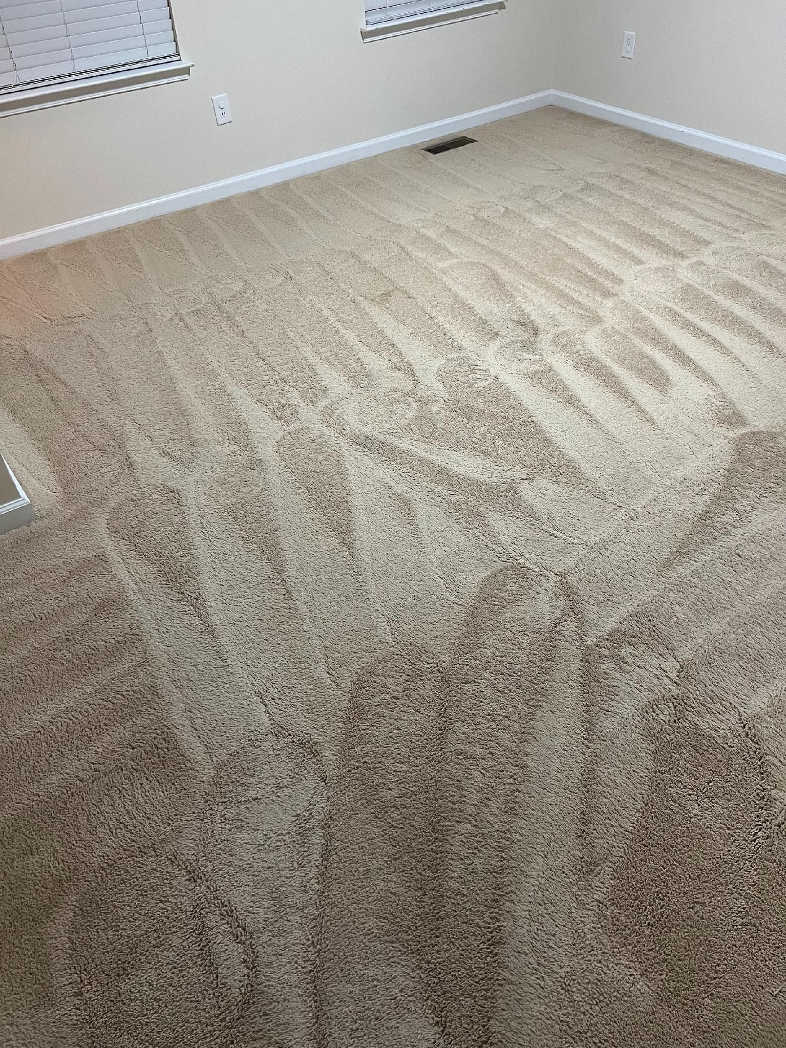Beige carpeted room, with angled sunlight creating pattern, empty.