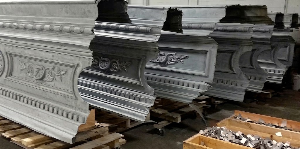 Rows of ornate white architectural moldings stacked on a workshop floor