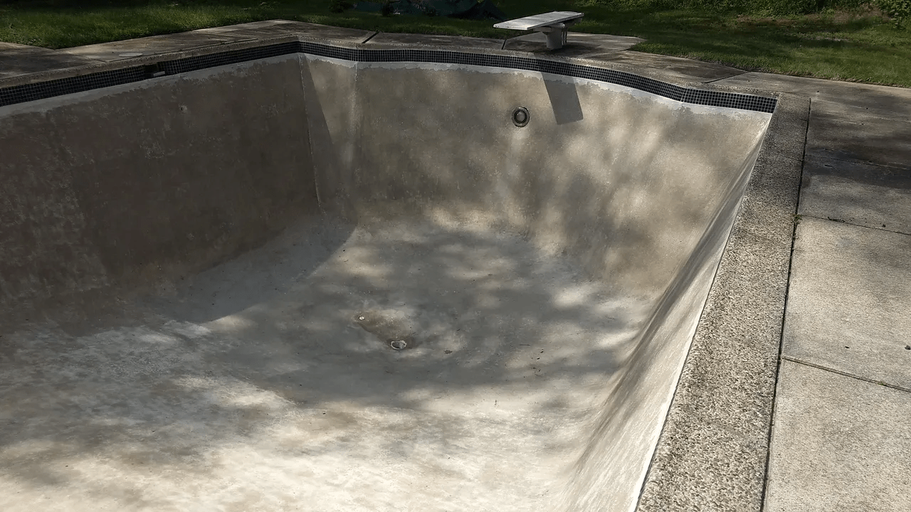 Empty concrete skate bowl with a smooth curved surface and sunlit shadows outdoors