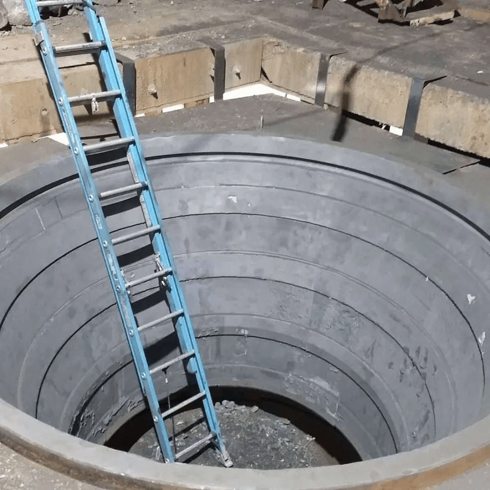Blue ladder inside a large circular concrete pit at a construction site