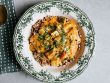 A bowl of chunky stew garnished with herbs on a floral plate