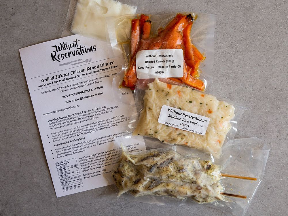 Recipe card and three plastic bags of prepared ingredients with carrots and rice on a white surface