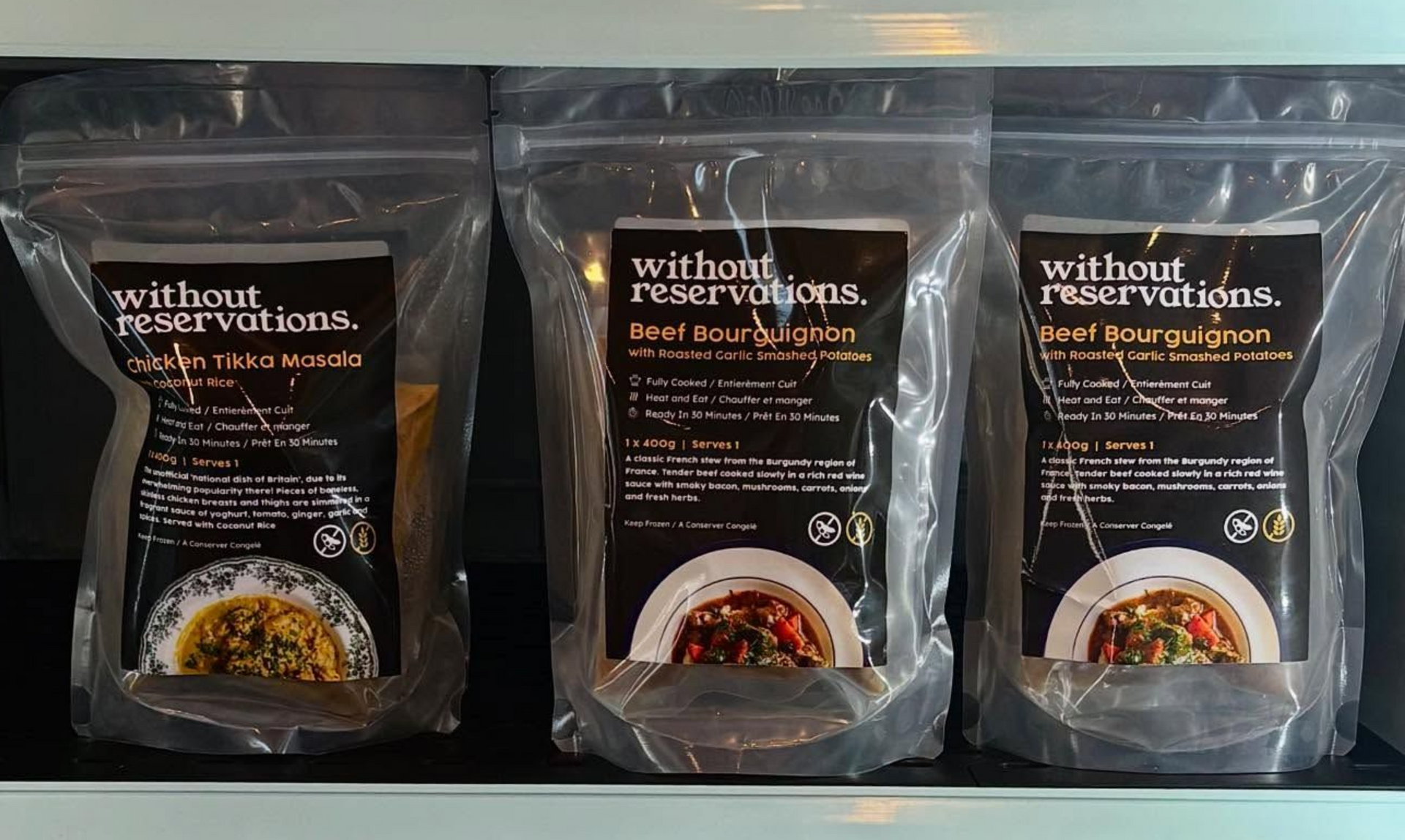 Three packaged food pouches labeled “without” stand side by side on a shelf.