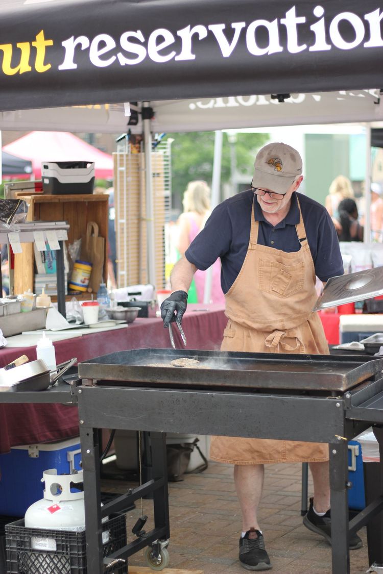 Vendor cooking food on a large flat-top grill at an outdoor market stall