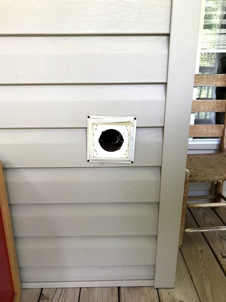 wildlife exclusion services A white vent on a beige vinyl siding wall. The vent is square with a round, black opening.