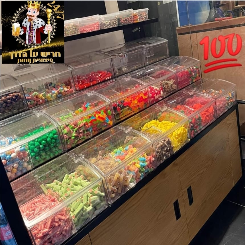 Counter display of clear candy bins filled with colorful sweets, with a red “100” price sign.
