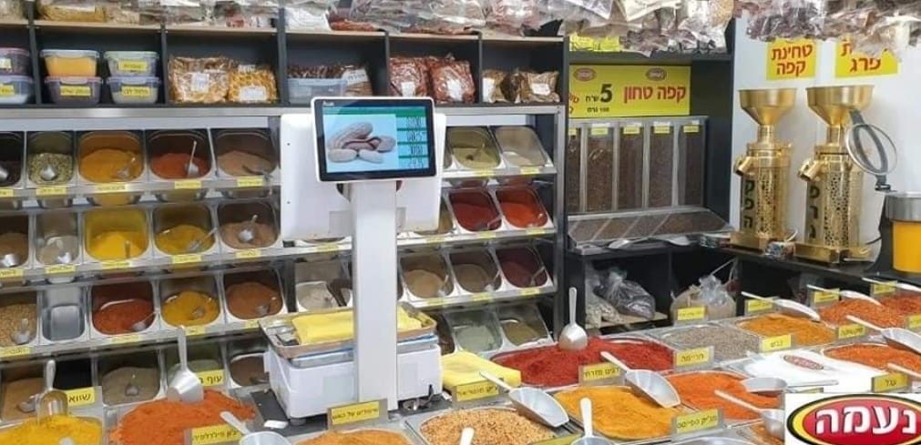 Grocery spice display with colorful jars, metal dispensers, and scoops in a store aisle