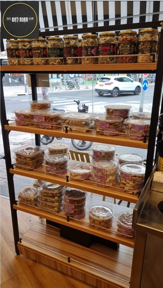 Shelf of assorted packaged snacks in a shop window, with street view visible behind.