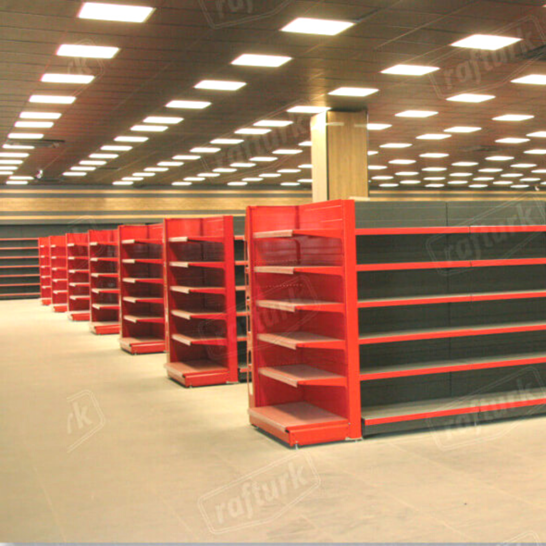 Empty store aisle with rows of red and black shelving under bright ceiling lights