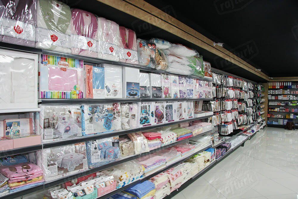 Aisle of packaged bedding and home goods on store shelves, with colorful boxes and pillows displayed.