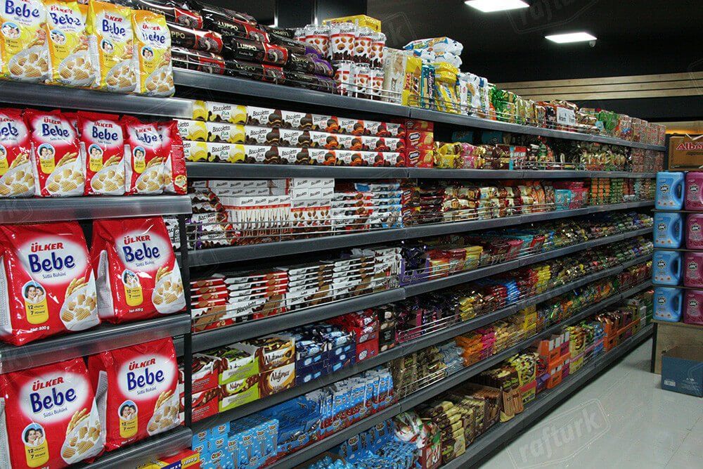 A grocery store aisle stocked with colorful packaged snacks and canned goods on long shelves