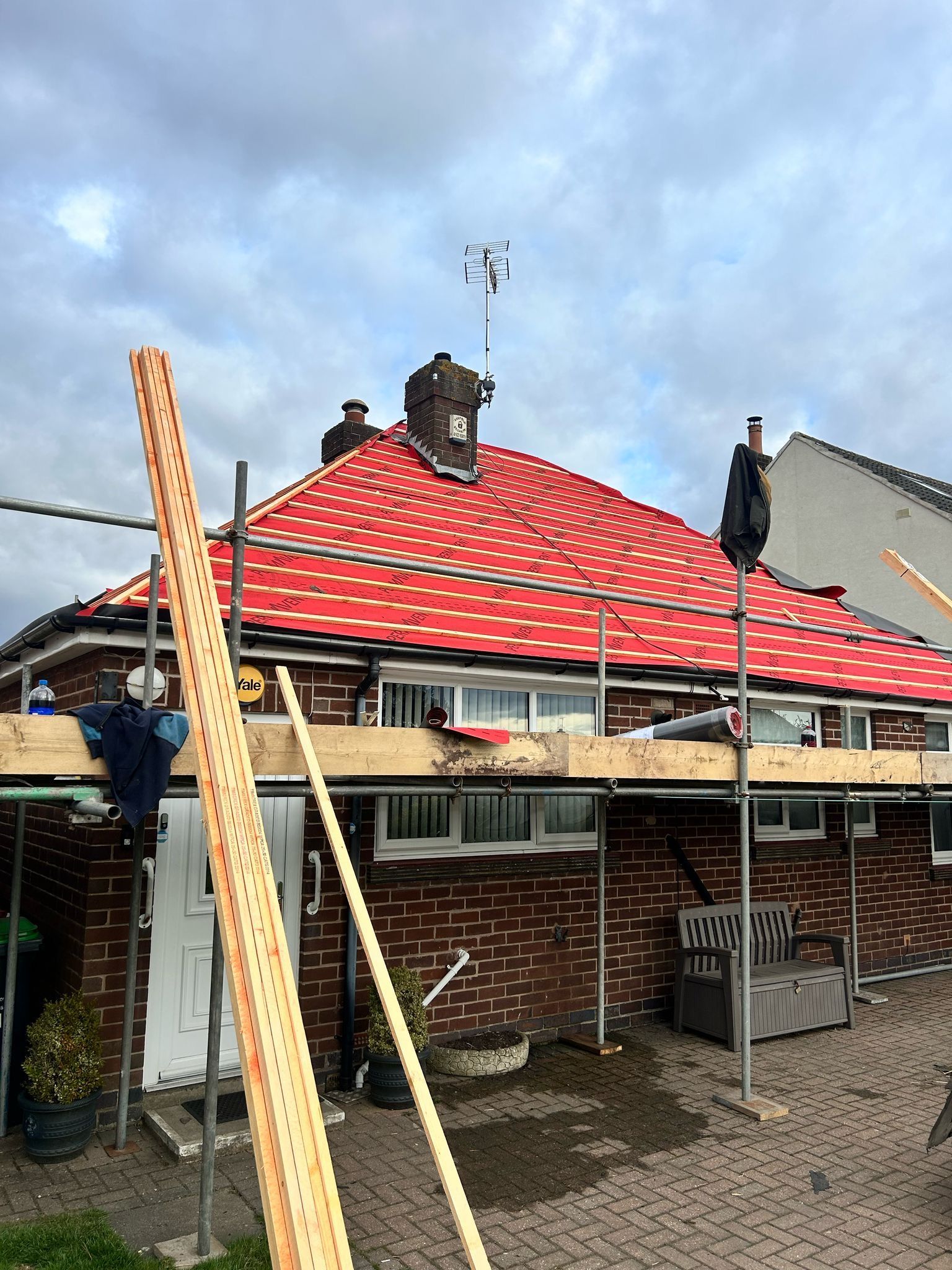 A house with scaffolding on the roof and a crane in front of it.