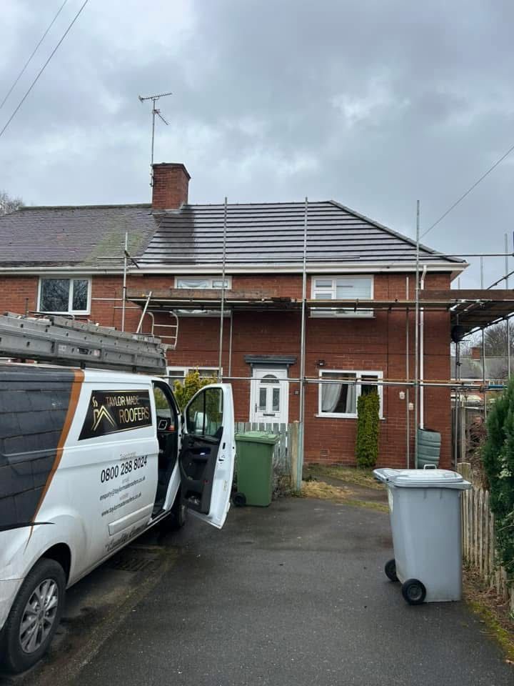 A white van is parked in front of a brick house.