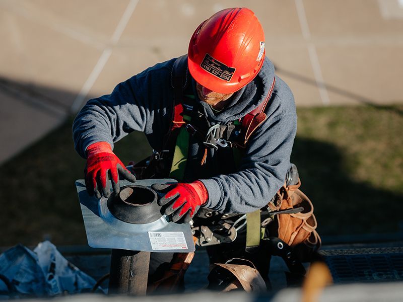 Un homme portant un casque et des gants travaille sur une pipe.