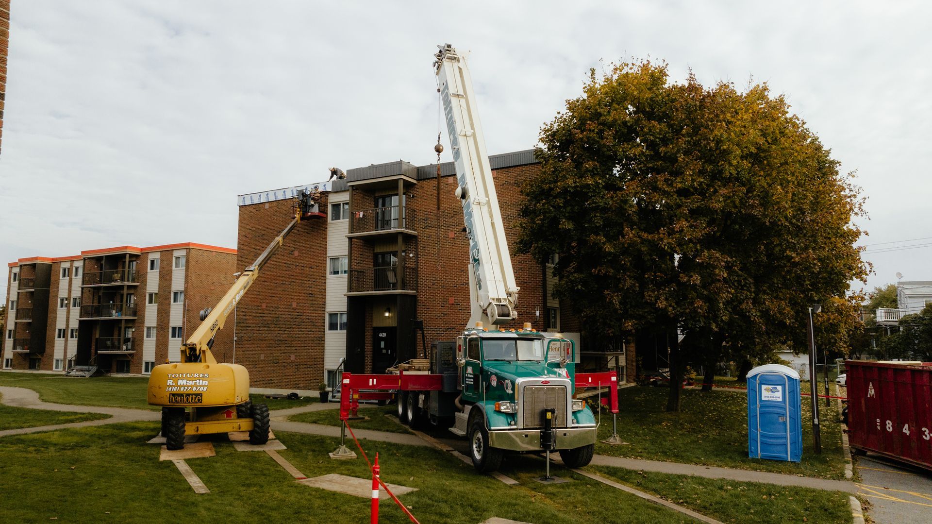 Un camion surmonté d'une grue est garé devant un immeuble.