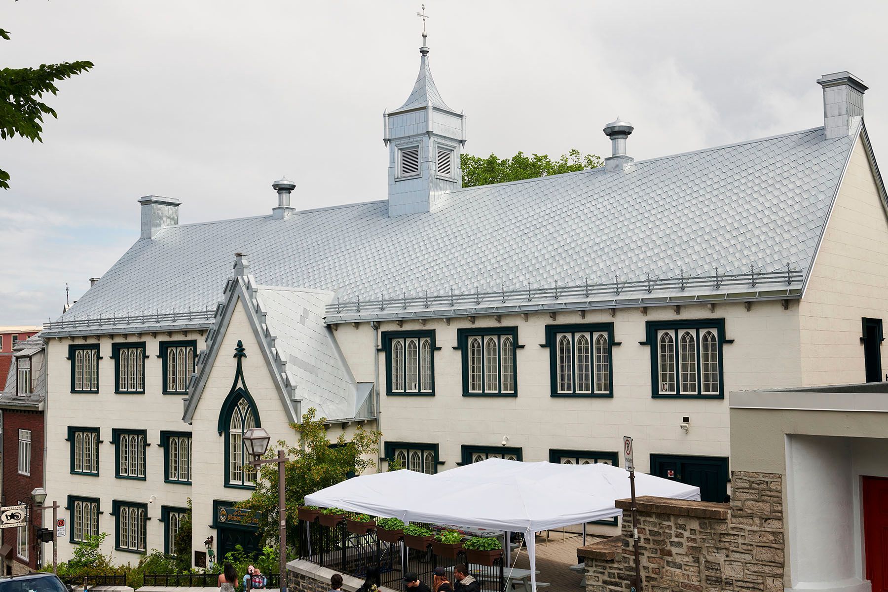 Bâtiment historique blanc aux fenêtres encadrées de noir et une petite tour sous un ciel nuageux