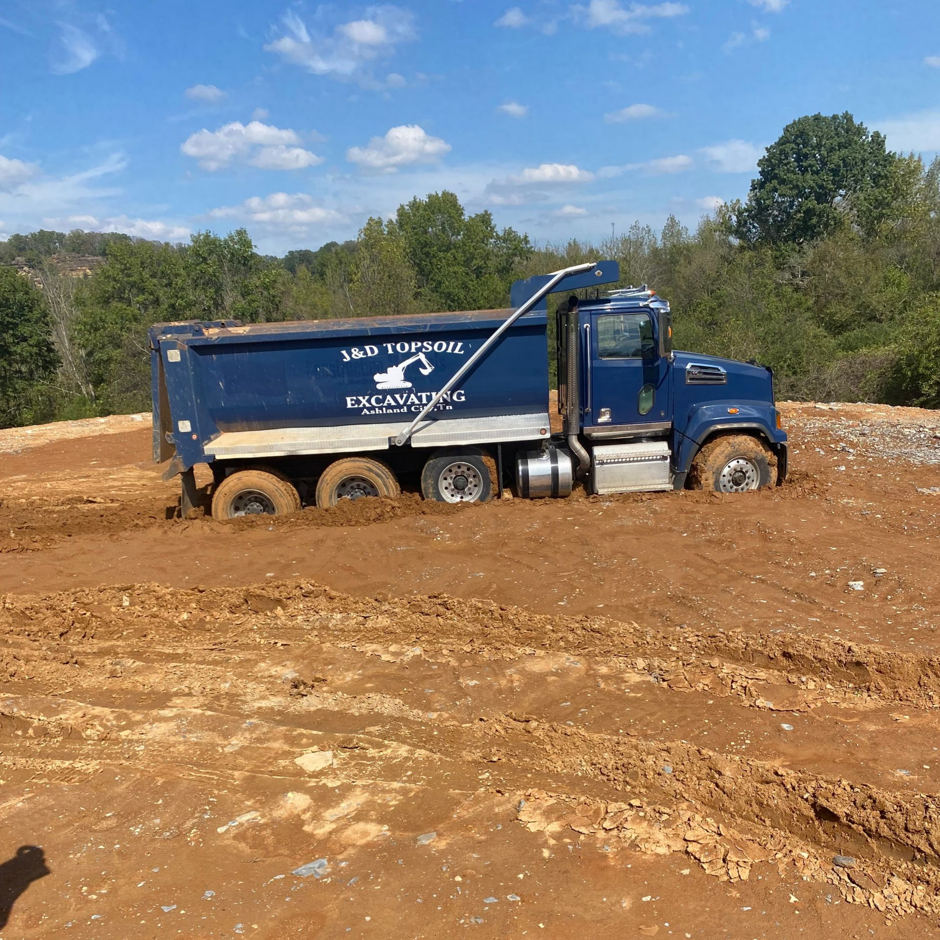 Blue dump truck in a muddy construction site under a partly cloudy sky Blue dump truck in a muddy construction site under a partly cloudy sky