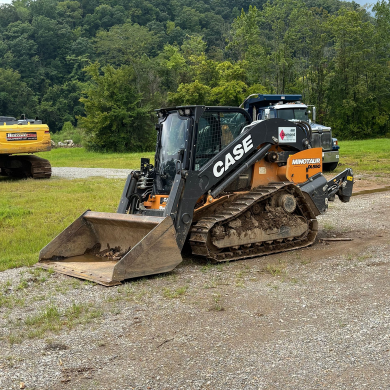 Yellow dump truck unloading red soil at a construction site
